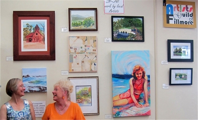 Jan Faulkner, left, has just mounted the labels for the paintings on the Fillmore Library wall and both she and Luanne Perez looks pretty happy about the current presentation.