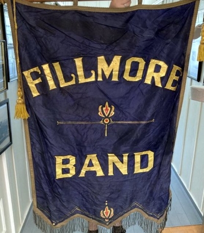 Pictured above is a blue banner with gold lettering that reads, “Fillmore Band”. Since the museum has no reference to the Fillmore Unified High School, they believe it was for the Fillmore City bands organized by Frank Erskine and Clarence Arrasmith. Photo credit Fillmore Historical Museum.