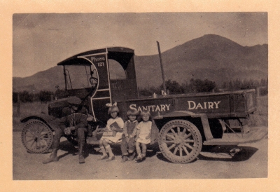 Sanitary Dairy truck in 1925, with Cliff, Dorothy, Russell and Evelyn Hardison sitting on the truck. Children would jump on and off the running boards to deliver milk.