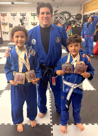 Pictured above left is Amelia Andrade who swept both the gi and no-gi divisions to claim double gold in the 7–8-year-old, 70 lb. female white belt division. Center is Coach Michael Torres, right is Dax Camacho who earned a bronze in gi and a silver in no-gi in the 60 lb. kids white belt division. Photo credit Michael Torres.
