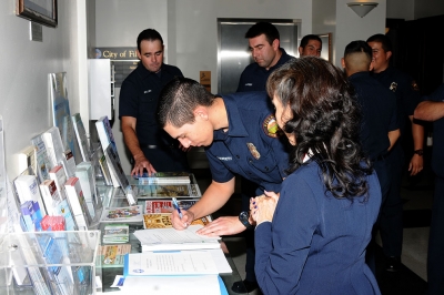 Fillmore Fire’s new volunteer firefighters are shown signing their swearing-in certificates at the city hall brochure table.
