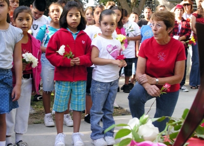 (l to r) Briana Mendoza, Jimena Cortes, and Aurora Aguilar with Mrs. Catalano listen and sing to “This Land Is Your Land.”