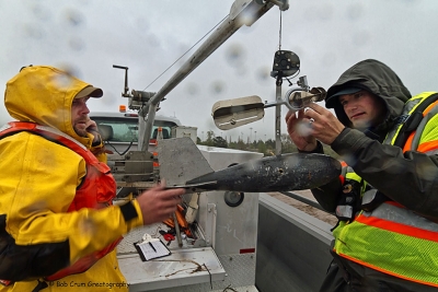 (l-r) Matt Melchiorsen and Mike Gaedeke readjusting the Price AA stream flow measuring device above the lead weight. Seeing spots? Relax. Your eyes are OK. The spots are water drops on the lens. It was raining!