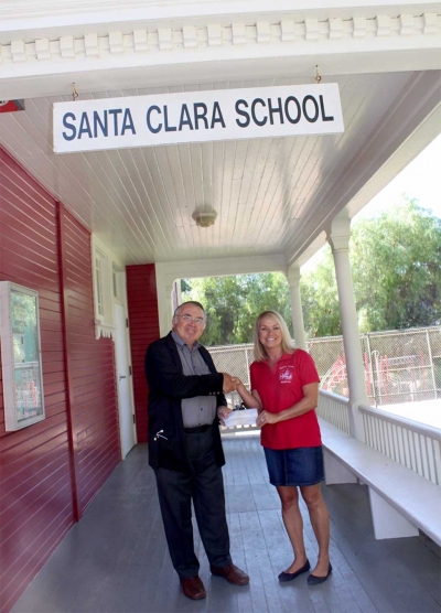 Dr. Gosta Iwasiuk present a check to Kari Skidmore, Principal.