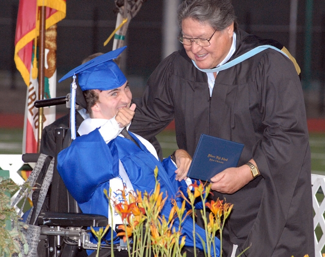 David Hynes gives a thumbs-up to the audience as FUSD boardmember Tony Prado presents him with his graduation diploma.