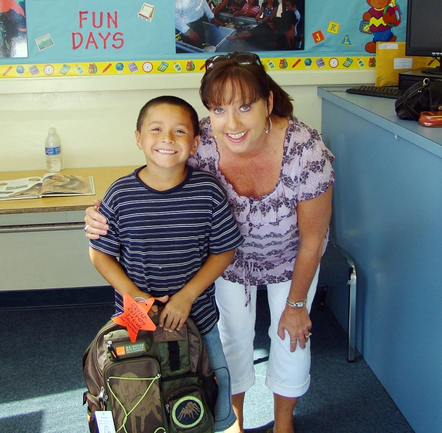 Smiling San Cayetano 3rd grade student Javier Soltero receiving a new backpack from Debbie Montoya who represents The Dream Fund Outreach Foundation.