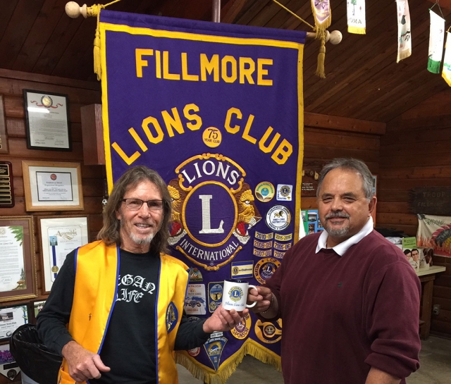 (l-r) Fillmore Lions Club Member Paul Benavidez presenting a Lions coffee mug to Ernie Villegas as a thank you for speaking to the club members. Photo courtesy Brian Wilson.