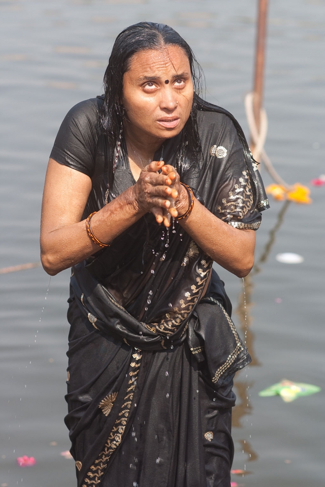 A woman offering up prayers as part of her morning puja on the bathing ghat in Ujjain, Madhya Pradesh. Photograph by Paul Hanson.