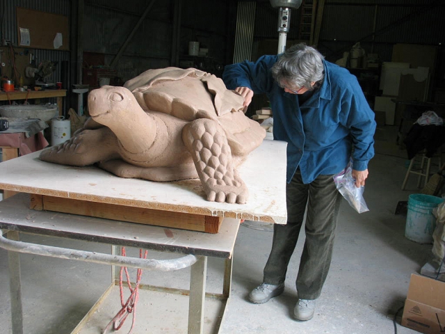 Toth checking clay model for turtle sculpture.
