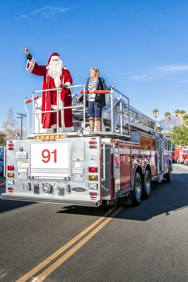 'Twas the week before Christmas, When all through the town, No one was stirring, not even a clown; The kids lined the street with caution and care, In hopes that St. Nicholas soon would be there. Alas, with a horn blaring and a siren screaming, Santa arrived on a firetruck delivering him to the fire department. No sooner had jolly ole St. Nick descended from big red truck when children rushed him for a group hug. Walking along the endless line of young and older... Santa gleefully dispensed Christmas cheer. Inside, Santa took up his customary position... the big chair in the fire department next to the Christmas tree. With a twinkle in his eyes and a mighty ho ho ho, children took turns sitting upon his knee whispering their secret Christmas list in his ear as parents strained to hear. Upon the traditional Santa photo taken, the children rushed to the toys piled high on the nearby tables. Decisions... decisions... decisions! Toys in hand, the youngsters moved along to the next station where they were fitted with a appropriately-sized, colorful body-warming winter coats courtesy of the Santa Clara Valley Legal Aid’s Coat Drive. While the winds blow... and old-man winter chills the air... toasty the kids all will be. Food Share provided bags of local fruit for one and all.
Outside what to my wondering eyes did appear but of course two powerful reindeer that brought Santa to Fillmore. Around the corner, FAA popcorn and 4-H cotton candy. Wow, what a wonderful Fillmore Christmas morning. A hearty thank you to all that make the Fire Department toy drive such a memorable Fillmore moment. Given the joyful smiles on all the faces, quite the experience to remember... one day in December. 
From all at the Fillmore Gazette, may everyone enjoy the experience of a very Merry Christmas. Photos and Story by Bob Crum. 