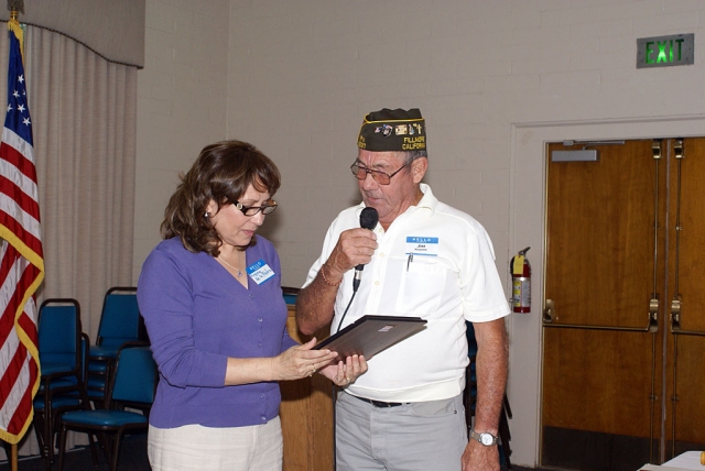 Virginia de la Pietra receiving a commendation from Jim Rogers for her work on the flags in town.