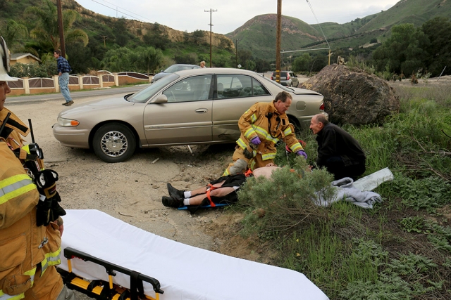 On Friday, January 30th, a two-vehicle collision took place on Grimes Canyon Road at San Marino Oil Company Road at approximately 4:15pm. A motorcycle apparently clipped an oncoming car, causing the car to spin into a boulder. The driver of the car was injured and attended by Fillmore Fire Dept., above. The motorcyclist received moderate injuries.