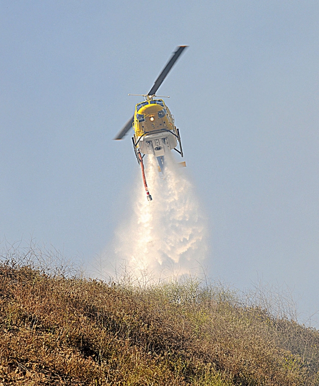 A Ventura County Sheriff’s helicopter douses flames above Highway 23 on Grimes Canyon, Wednesday. The brush fire consumed approximately 5 acres and was quickly extinguished by county firefighting units at about 6 p.m. Cause of the fire is under investigation.