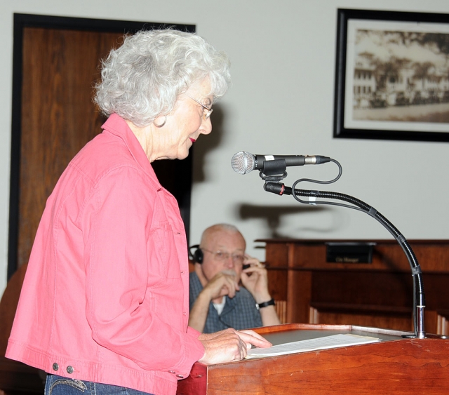 Jean Westling, speaking at the October 9, 2012 council meeting, with husband Clay Westling in background with headphones.