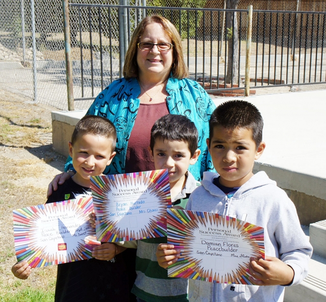 Isaiah Hernandez, Bryan Hurtado, and Damian Flores are congratulated by San Cayetano Principal Jan Marholin on receiving their Personal Success Award certificates.