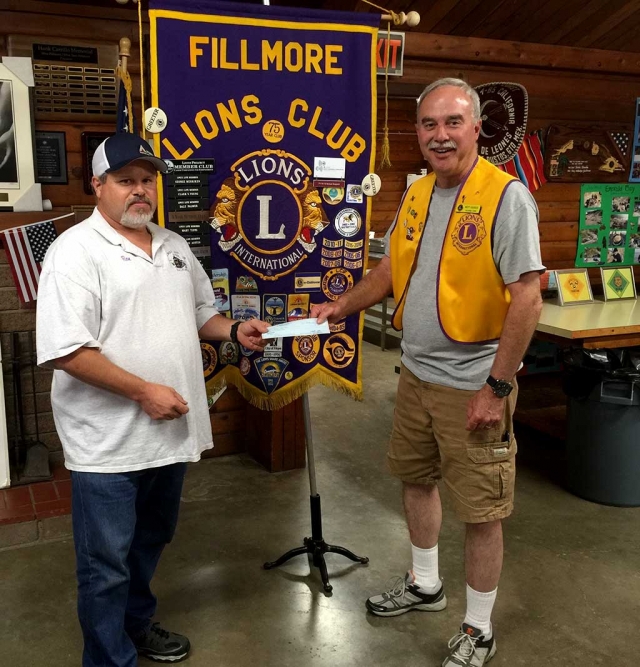 Brett Chandler, Scout Master for Fillmore Troop 406 and treasurer for the Fillmore Lions Club, accepts a $500 check from Lion Ron Smith at a recent meeting. The lions support the troop which shares the scout clubhouse with he Lions club.