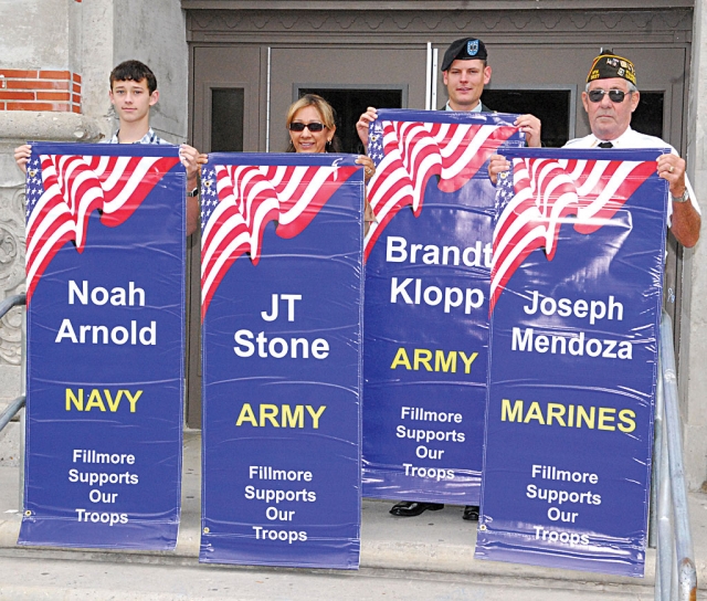 Thursday, July 8th, there was another installation of banners held on the front steps of Fillmore High School. Pictured (l-r) Ethan Arnold, brother of Noah Arnold, Annette Fox, mother of J.T. Stone, Captain Brandt Klopp with his own banner, and Jim Rogers holding Joseph Mendoza’s banner.
