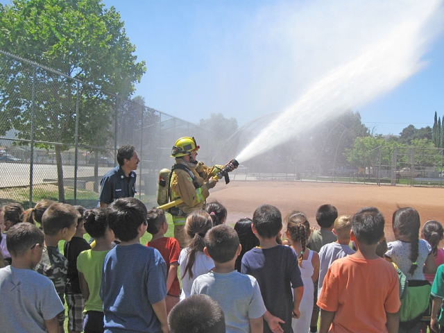 Capt. Al Huerta looks on as a Fillmore Firefighter shows the kids the power of the fire hose.