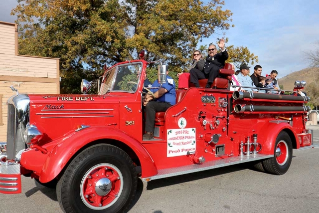 Piru Parade Grand Marshal Fred Ponce and his wife Yvonne Ponce wave to the crowds as they pass on the Vintage Fire Truck provided by Piru Fire Station.