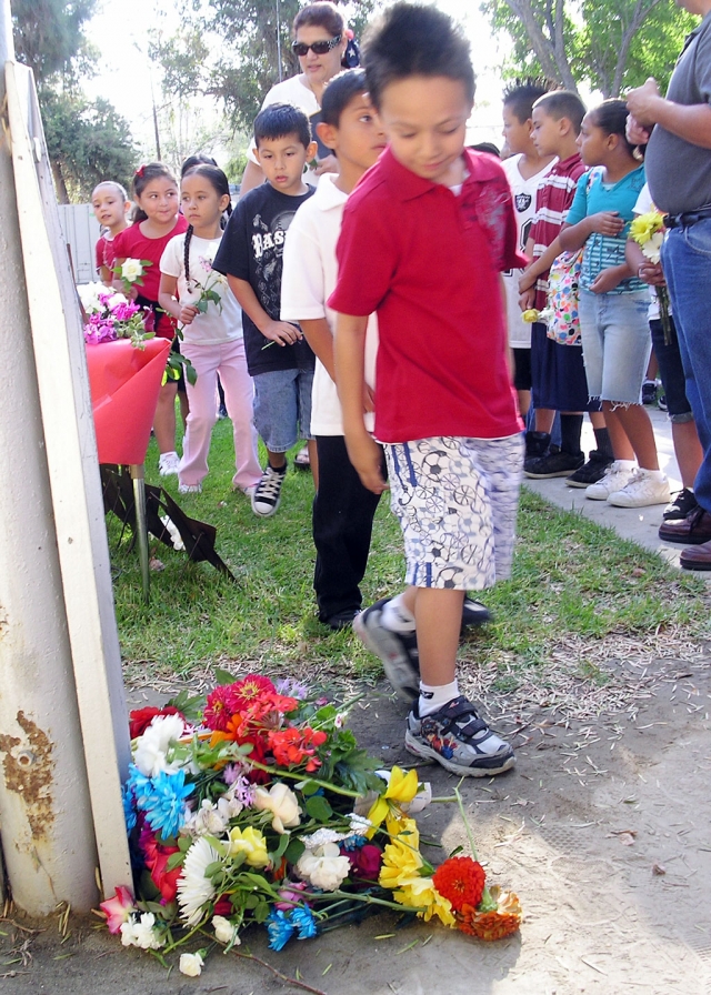 Jesus Ramirez places his flower at the base of the flagpole.