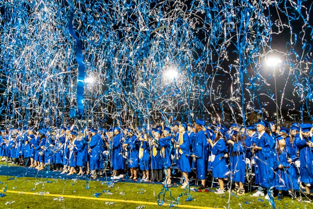 Photo of the Week: "Tassels crossed to other side of the mortarboard (caps), graduates celebrate by firing blue & white streamers into the air" by Bob Crum. Photo info: Canon 7DMKII camera, manual mode, Tamron 16-300mm lens @16mm. Exposure; ISO 10000, aperture f/10, 1/125th of a second shutter speed.
