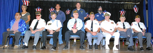 Fillmore’s war heroes honored at Middle School’s Pride in America Day. From left, Fred Ortiz, Wendell Tilley, Richard Schuck, J. C. Woods, Jim Rogers, Don Gunderson, Bud Untiedt, and John Pressey. Standing (l-r) Ortiz’ daughter Julia, and veterans Gama Aguilar, Jess Garnica, and Vincent Cobb. This year’s program was attended by a disciplined and respectful student audience, and addressed by honored guest speaker Staff Sergeant Felix Gabriel Chavez, U.S. Army.