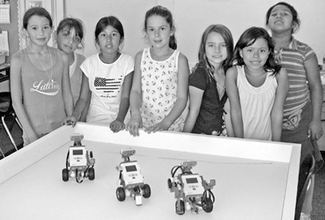 Shown are some of Brandi Walker’s 4th grade students working with robotics. The students need to use various math skills including reasoning and deduction in order to program the computer to make the robots move certain directions and pick up items. Upper grade teachers rotate teaching their students in the robotics lab. The robotics were purchased with NASA funds.