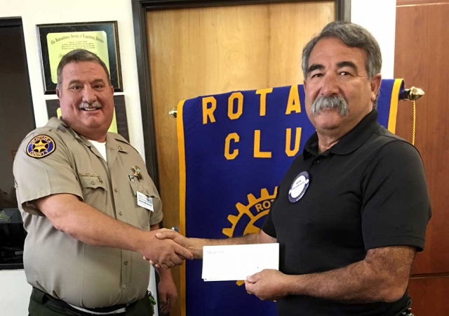 Police Chief Dave Wareham, left, presents Fillmore Fire Chief Keith Gurrola with a donation check for $500 from the Fillmore Rotary Club to go towards books for the Community Give Away which will take place December 16th.