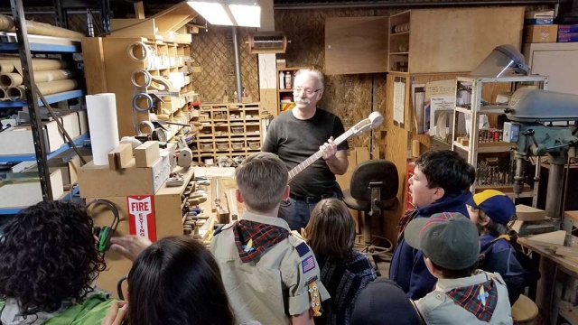 Tuesday, January 30th Fillmore’s Webelo Scout Troop 3400 toured Fillmore’s Packinghouse Creative. Picture above is the troop listening to Bruce Johnson, one of the craftsmen, teaching scouts about how he uses each tool in the guitar making process.