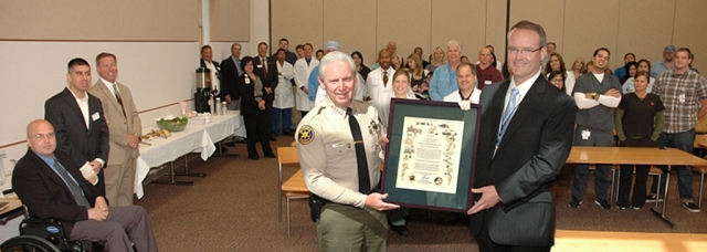 Sheriff Brooks presenting resolution to Mike Powers with HCA staff present.  Looking on at left are Senior Deputy Bill Meixner (wheelchair), Deputy Beau Rodriguez, and Undersheriff Mark Ball.