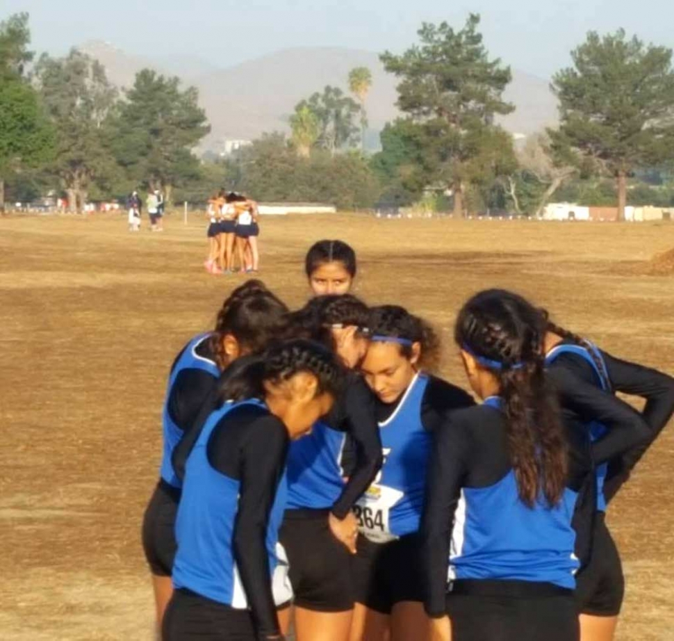 Fillmore Flashes girls cross country team huddle together before their race begins.