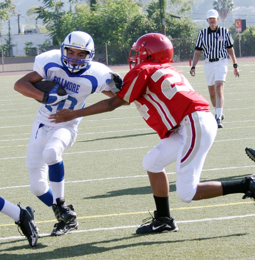 Mario Hernandez #10 (JV) puts his arm out to avoid the tackle. Hernandez also scored 1 touchdown.