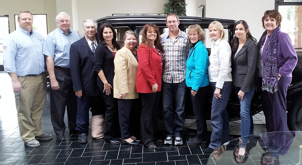 The board of directors and officers in front of an "antique" automobile in the William L. Morris showroom. The participants are (l-r) Rick Neal, Ron Lewis, Jim Mendrala, Rosa Martel, Maria Christopher, Cindy Jackson, Kevin Keehl, Kathleen McCreary, Donna Stewart, Talia Wunder, Kathy Long.