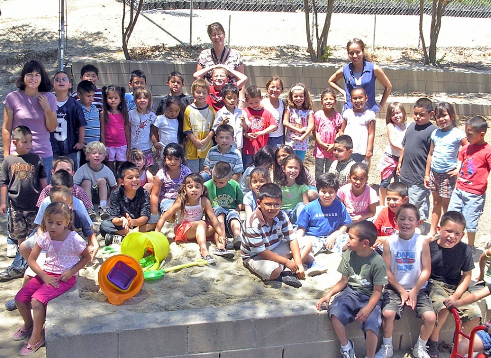 Piru Kindergarten students around their sandbox with teachers (left to right) Mrs. Schaper, Mrs. DeMoss, and Mrs. Dollar.