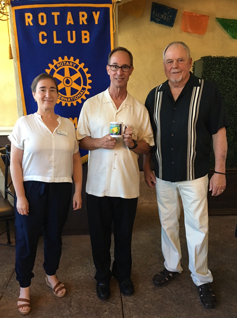 Last week’s Rotary Club speaker was Rick Schroeder from Many Mansions, along with Dalit Shlapobersky. Rick stated that the affordable housing Mountain View Apartments are completed and in the process of interviewing potential residents. There are 77 units with 1-3 bedrooms and there is also a large community space. They are partnering with the Boys & Girls Club and will have a similar club/homework help site for resident students. Many Mansions also offers a scholarship program for resident students who are going on to higher education. They have various resources and help for adults also. The company has 18 housing complexes in Ventura County and four in LA County. Dalit is in charge of fundraising to augment funds from county, state, etc. Pictured are Dalit Shlapobersky and Rick Schroeder from Many Mansions, and Rotary President Dave Andersen. Photo credit Martha Richardson.