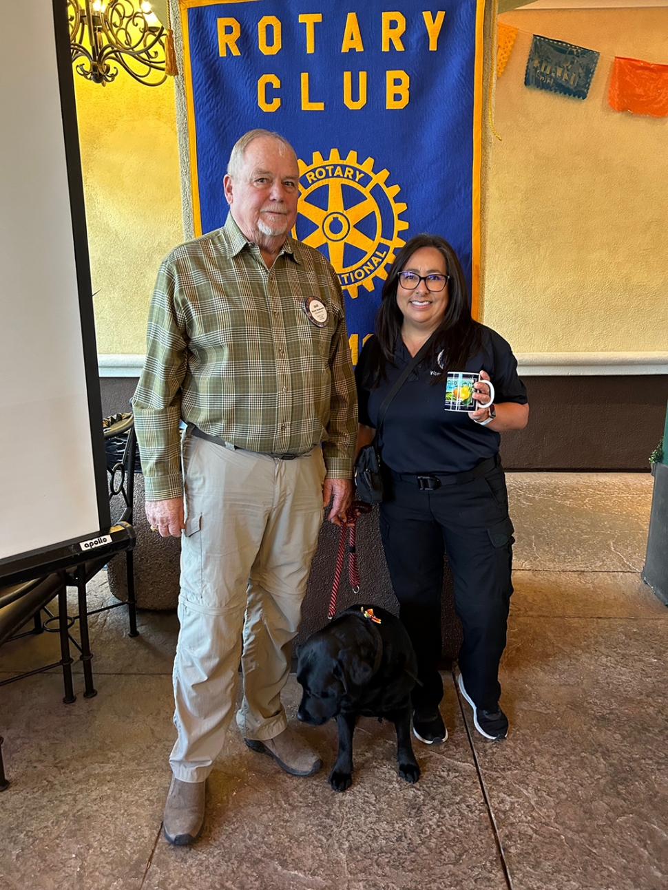 Carrie Broggie introduced Andrea Stewart, D.A. Victim Advocate, with the Courthouse Dog Program. Andrea is part of the Victim’s Assistance Unit located at the Hall of Justice. Her dog’s name is Star, one of several which are trained to support and comfort victims. They may sit by the victim in the courtroom, or during initial interviews. The victim may pet the dog, or the dog may lay at their feet. This is especially comforting to children. This Program offers Camp Hope, a week of fun for children after all they’ve gone through. Pictured (l-r) Rotary President Dave Andersen, Andrea Stewart and Star.