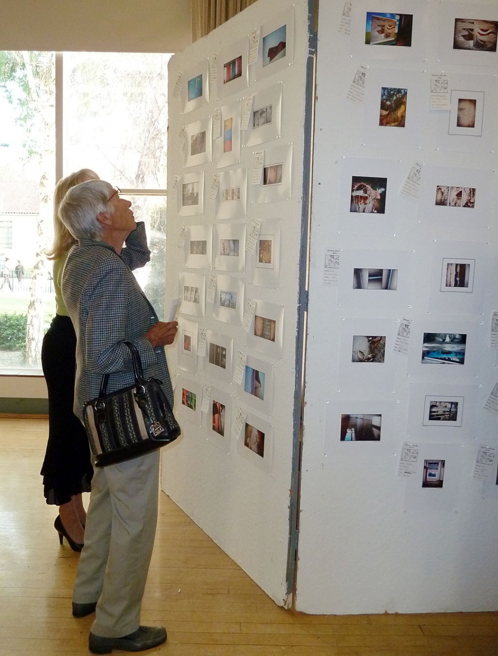 Sara Hansen and Jane David take a moment to view the pictures on display from photo class.