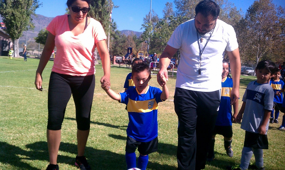 Escorted by his coaches, Emiliano Martinez scores a goal during his AYSO game.  
