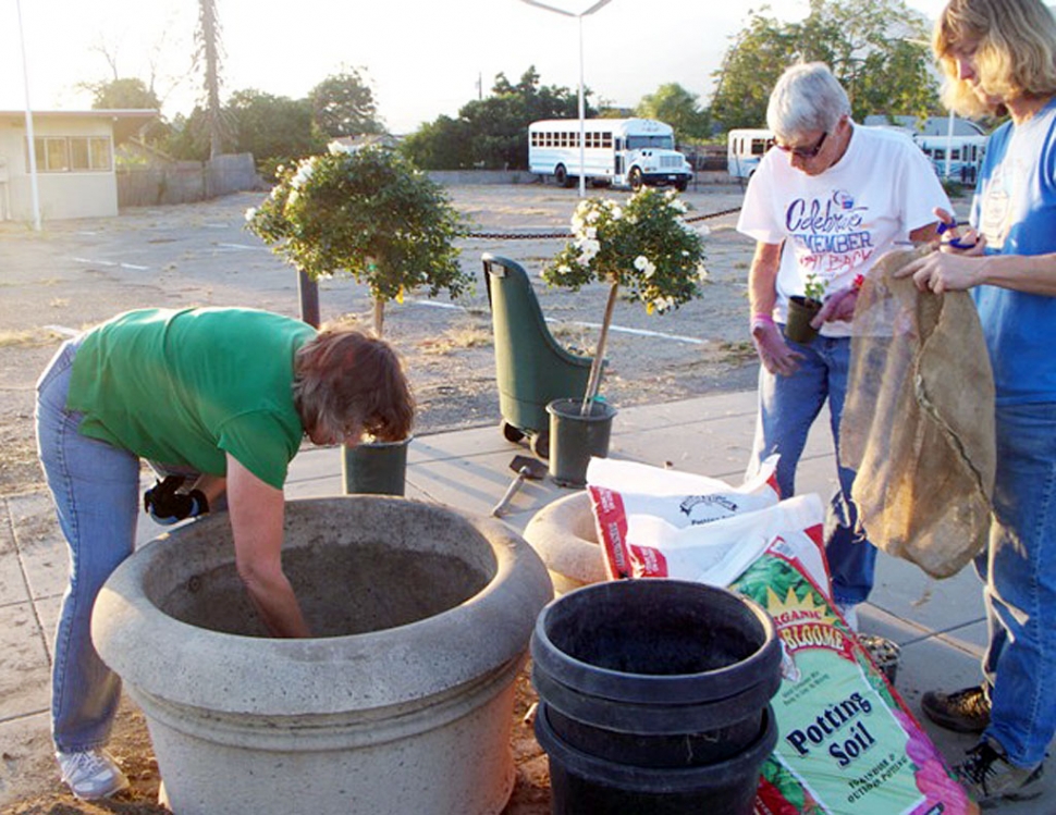 Patti Walker, Sarah Hansen & Cindy Klittich work on the Soroptimist sponsored planter, preparing it for planting.