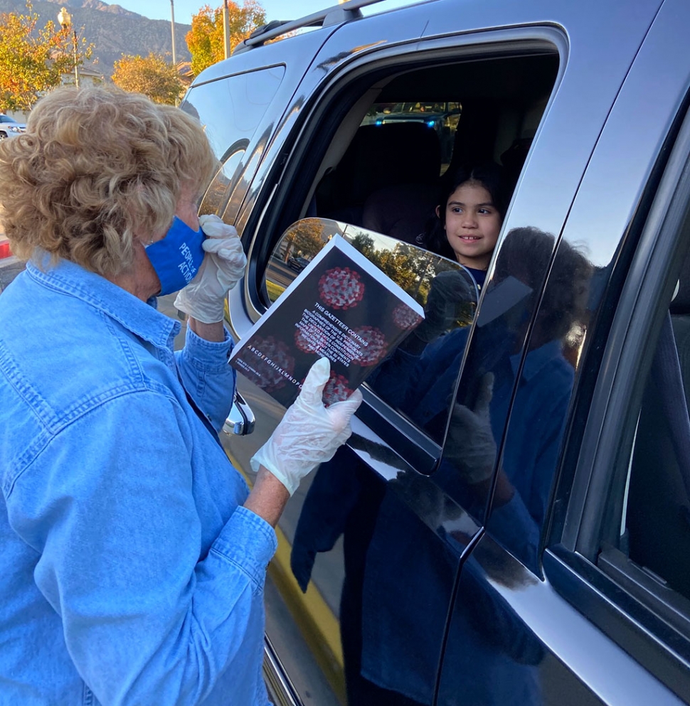 Rotary member Martha Richardson is shown handing a book to a Fillmore student as they drive by.