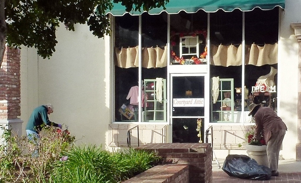 Sarah Hanson, left, a member of the 2020 Vision Civic Pride Committee and a friend take time to keep the downtown planters clear of trash and maintained in front of new business “Courtyard Attic”