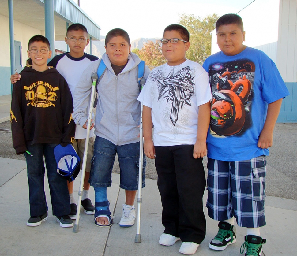 Fifth grade students back to school at San Cayetano surround fellow 5th grader, Fernando, who injured his foot playing football.