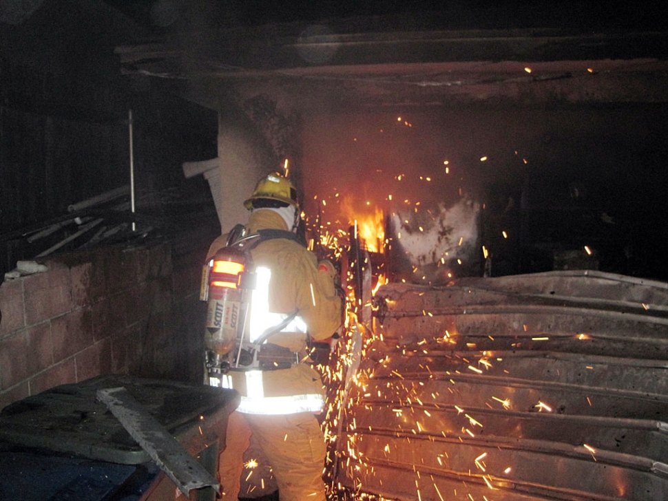 Firefighter Rick Neal of the City of Fillmore Fire Department uses a rotary saw to cut down an aluminum garage door at a residential structure fire that occured early Monday morning in the City of Fillmore.
