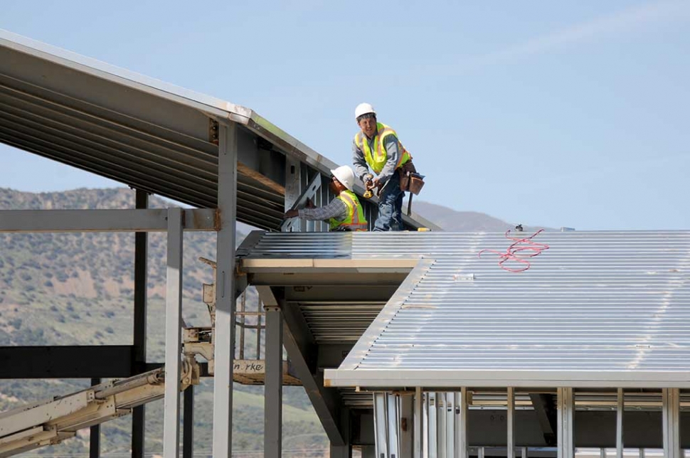 Construction workers working in the warm weather on the roof of the soon to be new fire station. 