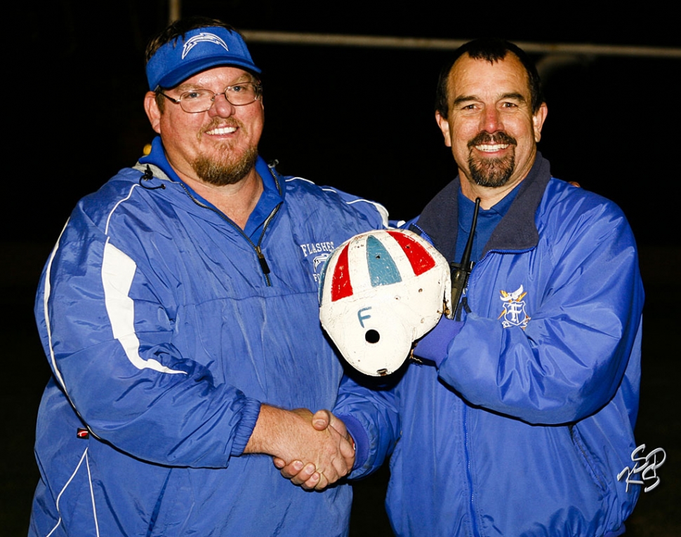 Coach Matt Dollar and Principal John WilbEr hold the leather helmet for the camera. Fillmore defeated Santa Paula last Friday night. It has been 2 years since we have had the helmet in Flashes territory. Photo by Carmelita Miranda, KSSP Photographic Studios, Fillmore.