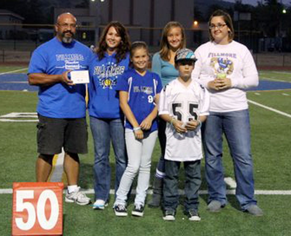 Max Pina Jr. presents a thank you plaque to the family of Walker Kozar at the beginning of Friday night’s varsity football game. The plaque will be hung in the BBQ area by the stadium snackbar, honoring Kozar’s years of barbecuing for the games.