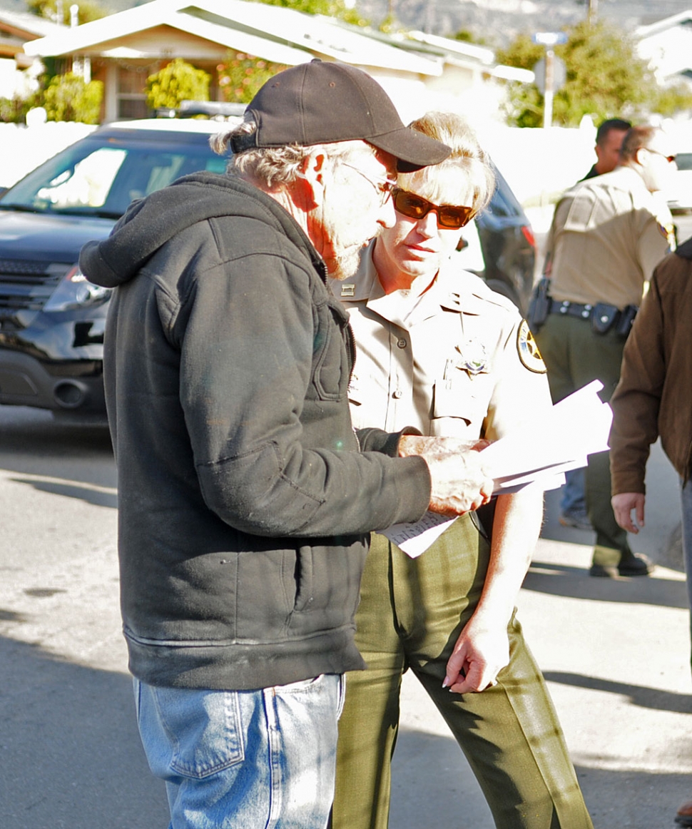 Sheriff’s Capt. Monica McGrath speaks with property owner Herbert Haase, as he holds the warrant served on him. Haase has refused to spray his citrus grove for the Asian Citrus Psyllid, an invasive, aphid-like pest.