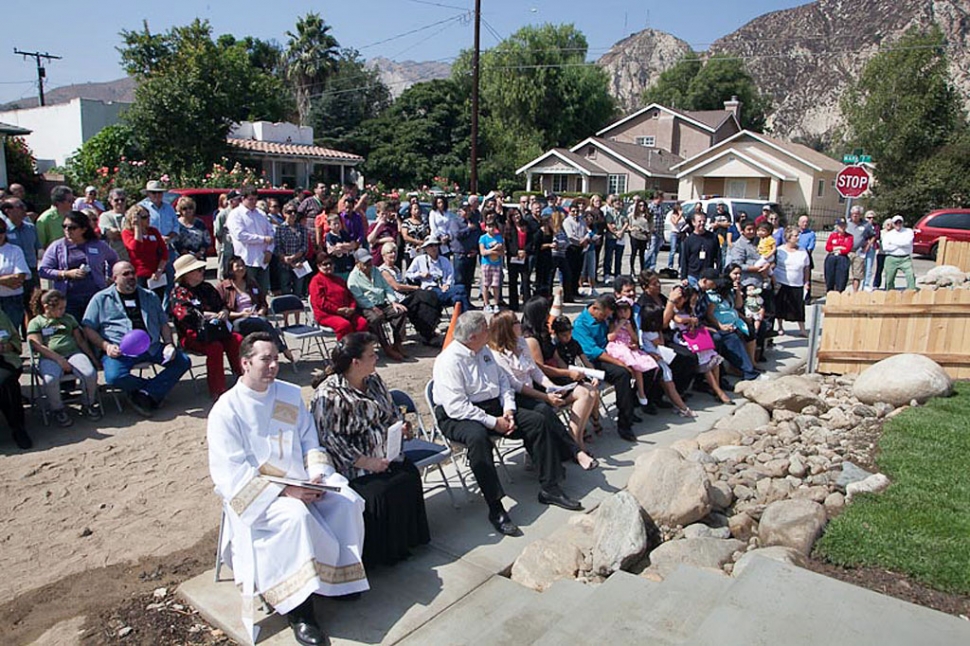 A crowd composed of sponsors, volunteers, family and friends of the Habitat for Humanity homeowner look on during the dedication.