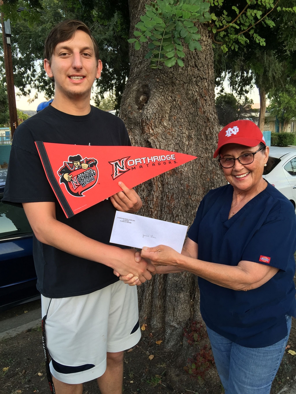 James Farr, class of 2012, one of the 29 Continuation Grant recipients receives his award from Scholarship/Grant Committee Member Becky "Sosa" Morales, class of '58.