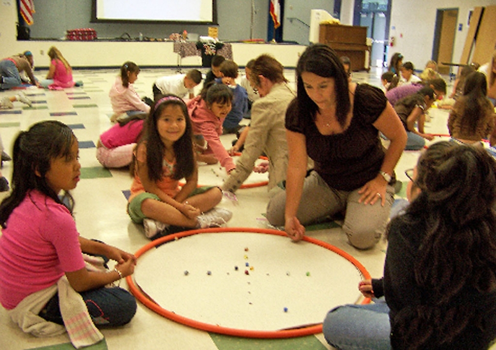 Mrs. Schieferle, Mountain Vista Principal, shows off her shooting skills to Arianna Salas.